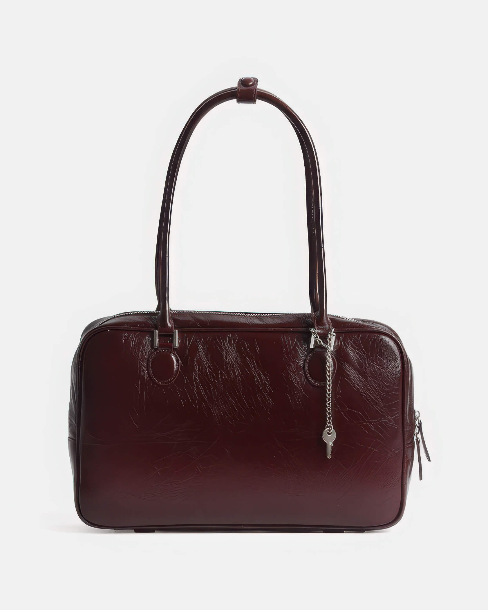 Front view of a rectangular dark red leather shoulder bag with decorative key keychain.