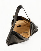 Top view into the open black slouchy faux leather handbag showing light beige fabric lining and inner zip pocket