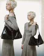 Dual view composition of blonde model wearing a black glossy faux leather slouchy shoulder bag with star rivets