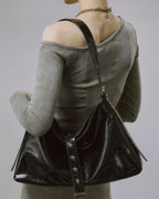 Back view shot of model wearing a black crinkled faux leather slouchy shoulder bag with silver star hardware