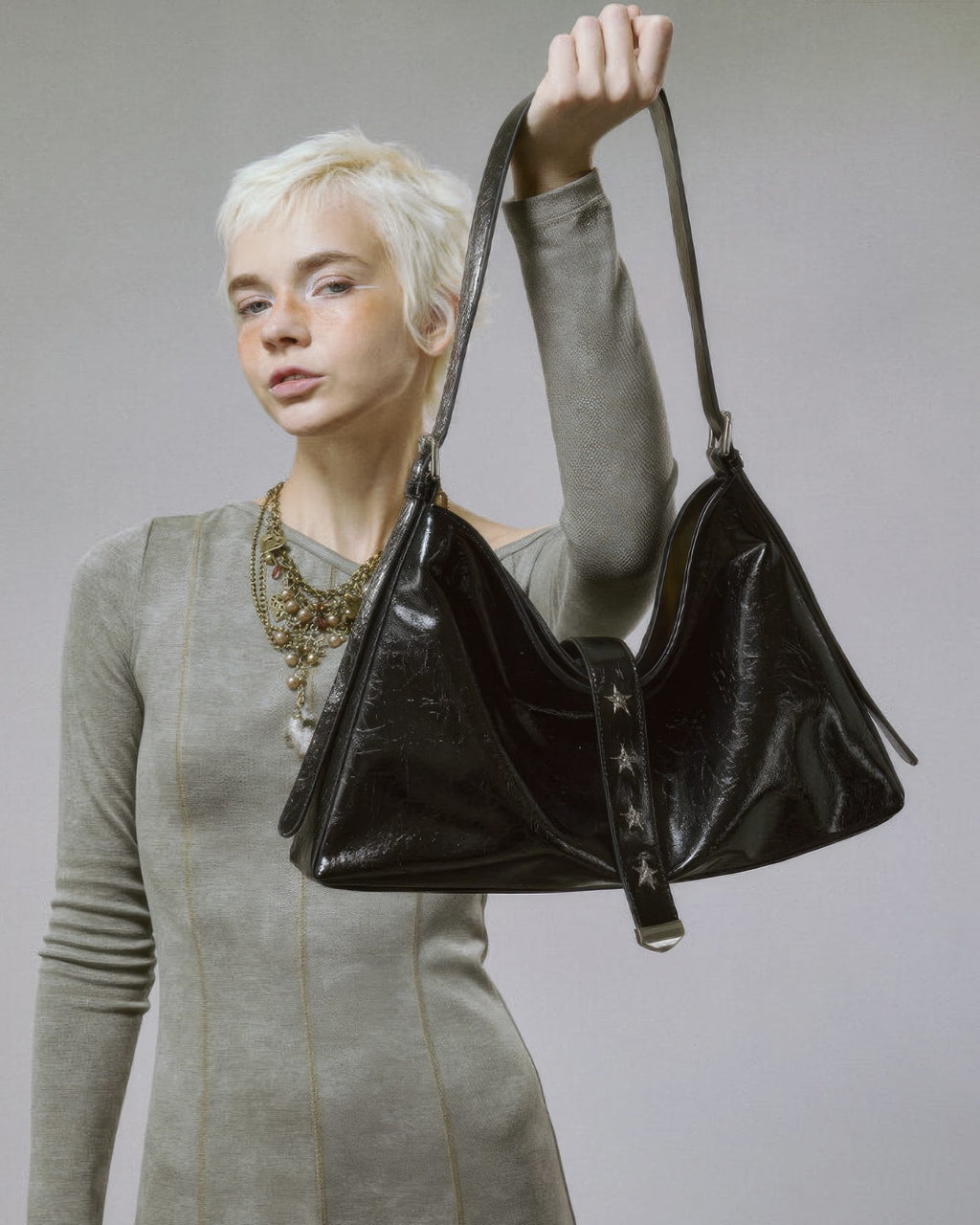  Blonde model lifting a black slouchy leather handbag by the shoulder strap showcasing its slouchy shape