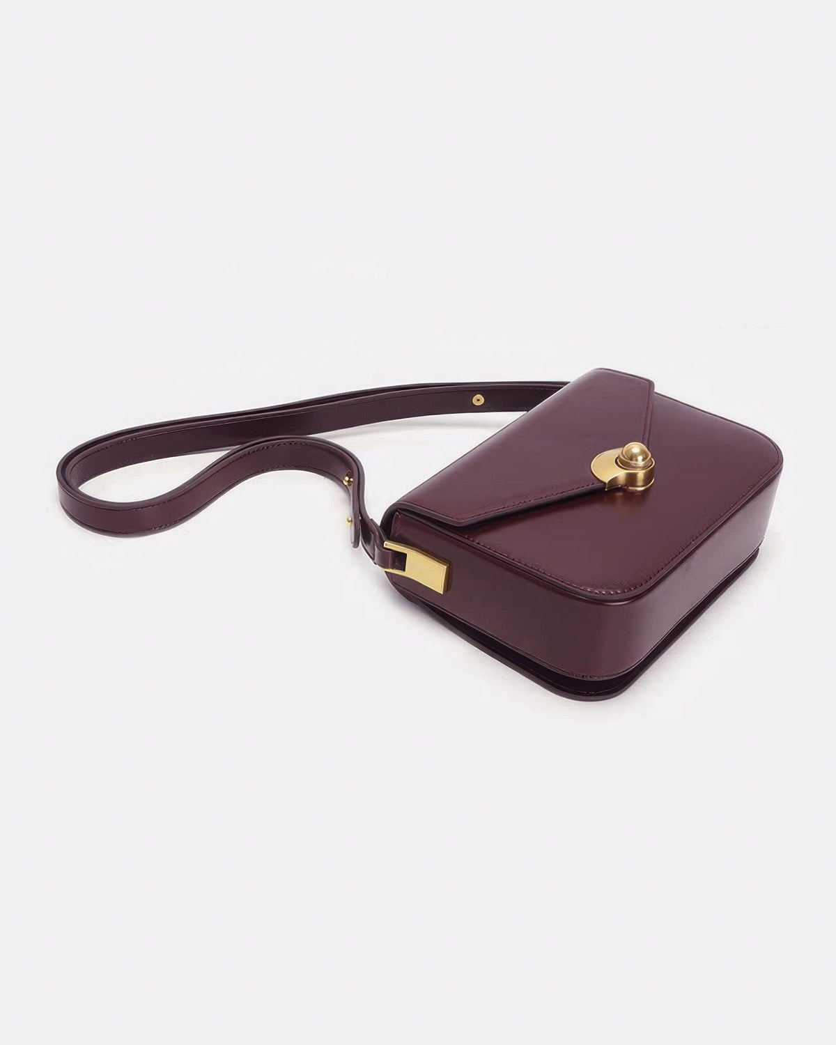Top-down angle of a dark burgundy leather turn-lock flap bag resting flat on a white surface.