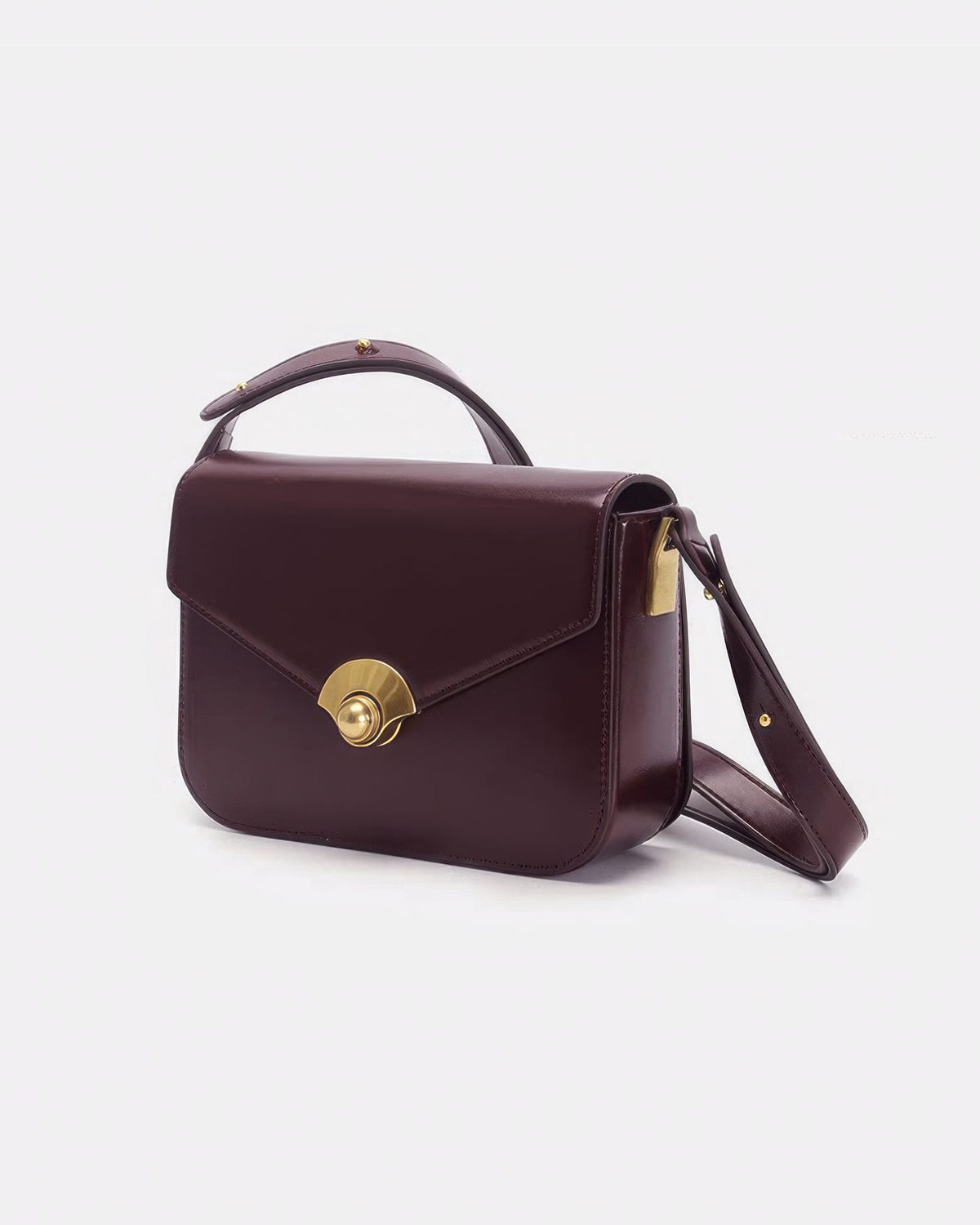 Side view of a structured deep burgundy leather flap purse with vintage gold hardware accents.