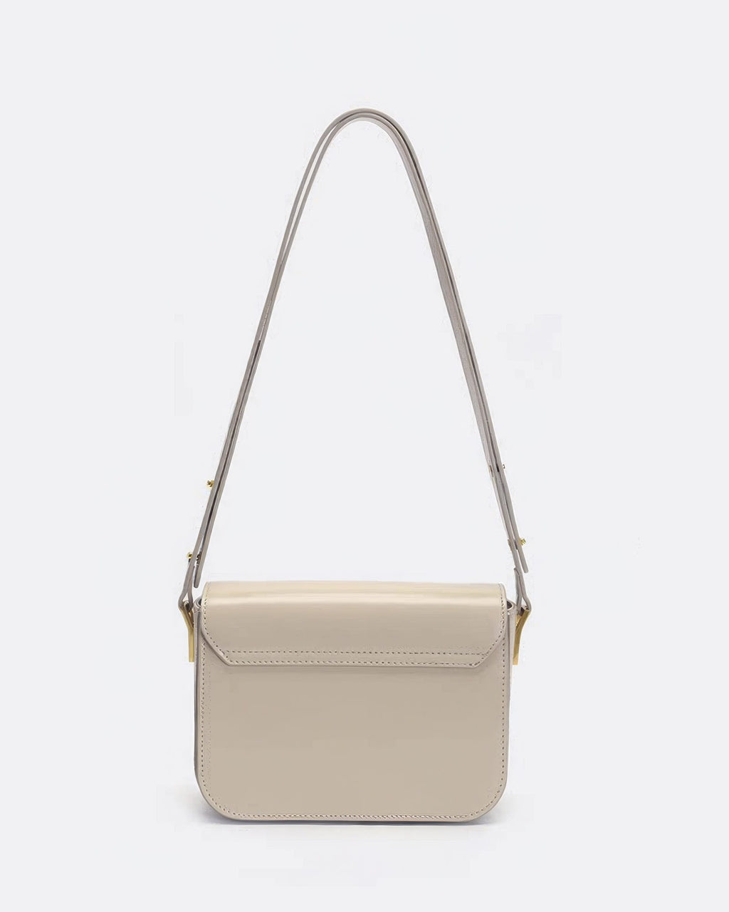 Rear view of an off-white smooth leather shoulder bag with clean stitching and gold strap connectors.
