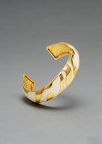 Side view of the Vintage Zebra Stripe Enamel Cuff Bracelet in cream and gold, featuring a bold wavy pattern and textured gold interior.