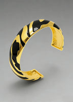 Perspective shot of the Vintage Zebra Stripe Enamel Cuff Bracelet in black and gold, showcasing the glossy enamel finish and wide cuff design.