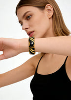 Side profile of a model wearing the black and gold Vintage Zebra Stripe Enamel Cuff Bracelet to show how it sits on the wrist.