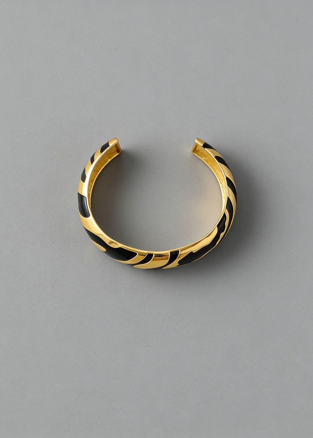 Overhead view of the black and gold Vintage Zebra Stripe Enamel Cuff Bracelet showing the open-back adjustable cuff style.