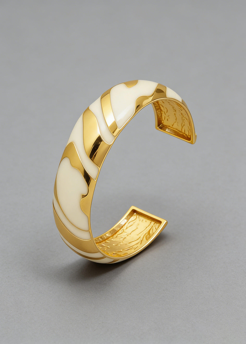 Angled view of the Vintage Zebra Stripe Enamel Cuff Bracelet in cream and gold highlighting the smooth enamel curves.
