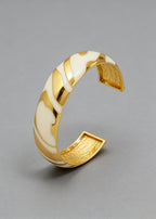 Angled view of the Vintage Zebra Stripe Enamel Cuff Bracelet in cream and gold highlighting the smooth enamel curves.