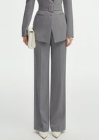 Lower-body shot focusing on the high-waisted, wide-leg grey trousers and the buckle detail of the suit's belt.