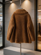 Back view of a cognac brown shearling wool pea coat with a wide collar on a clothing rack display