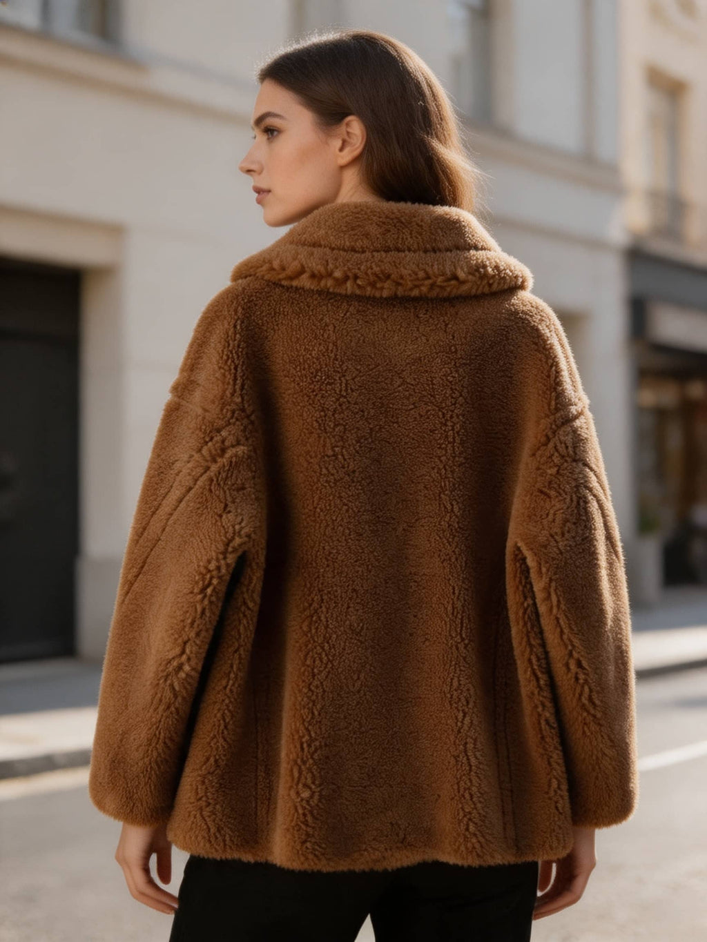 Back three-quarter view of a model wearing a cognac brown shearling wool pea coat outdoors