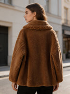 Back three-quarter view of a model wearing a cognac brown shearling wool pea coat outdoors