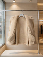 Inside lining and interior pockets view of an open cream shearling wool pea coat on a display rack