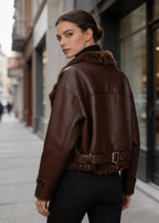 Back three-quarter view highlighting the waist belt buckle on a dark brown women's aviator jacket.