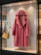 Front product display of a fuchsia pink hooded double-breasted shearling long coat styled with a yellow quilted handbag.