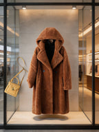 Front view of a brown hooded shearling wool teddy coat on display with a quilted yellow shoulder bag