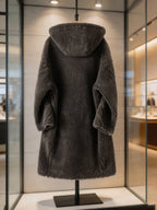 Back view of a dark grey long hooded shearling wool teddy coat on display in a store window