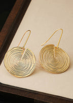 Detailed top-down shot of two gold textured disc earrings showing the delicate spiral ridges and thin ear wires.