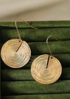 Pair of gold-toned disc earrings with a fine ripple texture displayed inside a dark green velvet jewelry box.