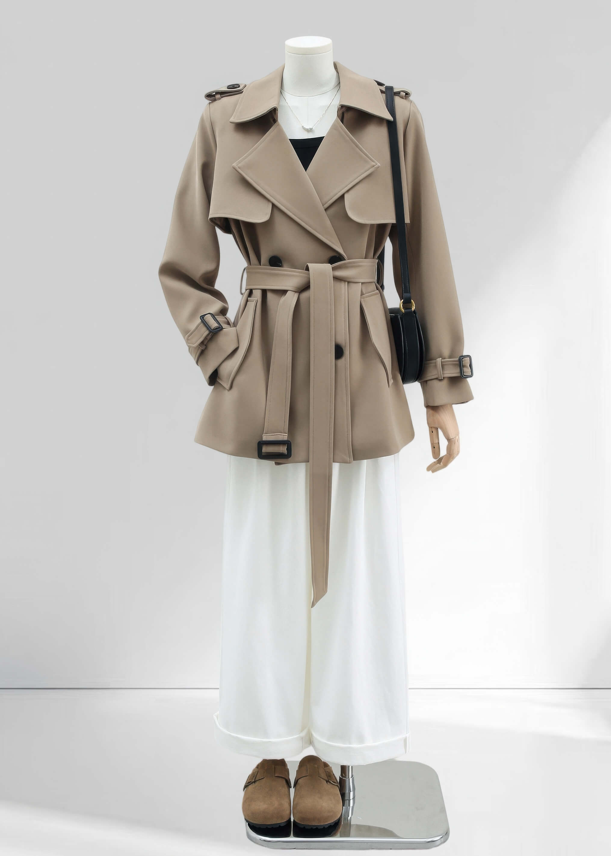 A full-length front view of the outfit. The khaki trench coat is paired with wide-leg white trousers and tan suede clogs, presenting a complete chic, professional look.