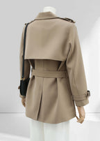 A back view of the short trench coat on the mannequin. This shot emphasizes the large storm flap across the shoulders, the central back vent, and the clean silhouette of the belted waist.