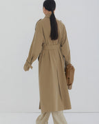 Back view of a women's long oversized trench coat showing classic storm flap and center vent detail.