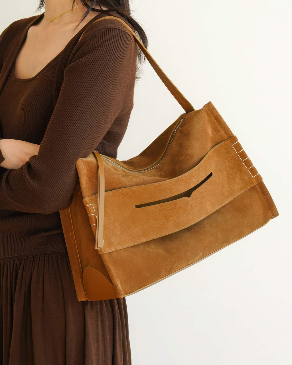 Lifestyle shot of the large suede shoulder bag being worn, showing how the soft material drapes against the body.