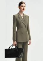 A woman wearing an olive green double-breasted tailored pantsuit, holding a large black leather tote bag.