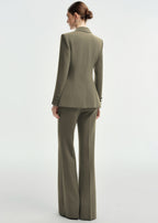 A rear view of a woman wearing an olive green tailored pantsuit, highlighting the structured back of the blazer and the fit of the wide-leg trousers.