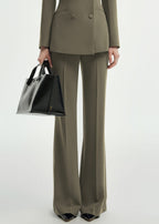 A close-up shot focusing on the lower half of the olive green pantsuit, showing the tailored trousers and a black leather handbag.