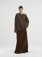 Full-length shot of a brown chunky knit wool sweater paired with a dark brown long skirt, minimalist winter outfit for women.