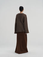 Rear view of a women's oversized brown wool knit pullover, showing the thick, textured weave and loose fit.