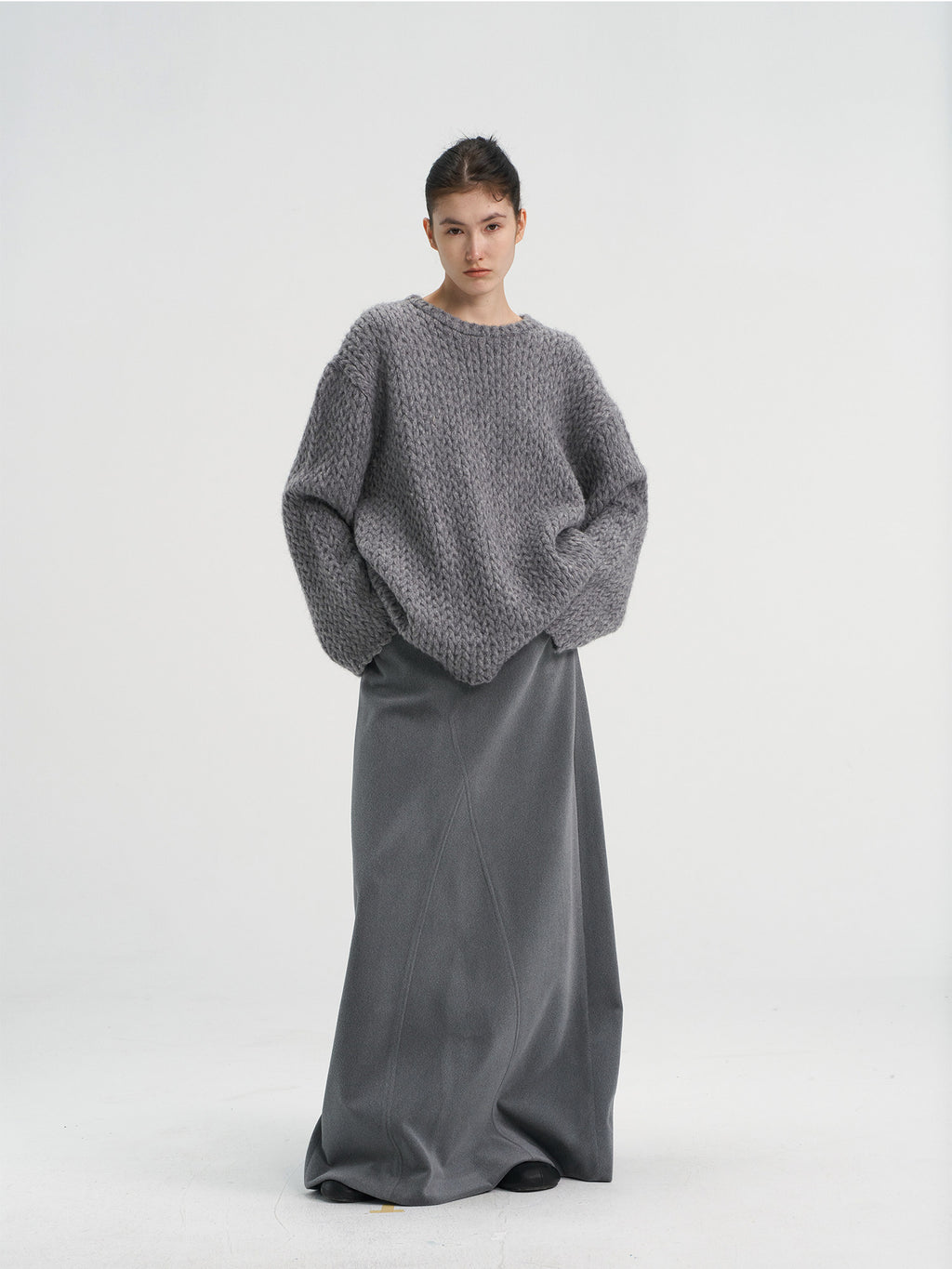 Front view of a women's oversized chunky wool blend knit sweater in heather grey, styled with a matching grey maxi skirt.