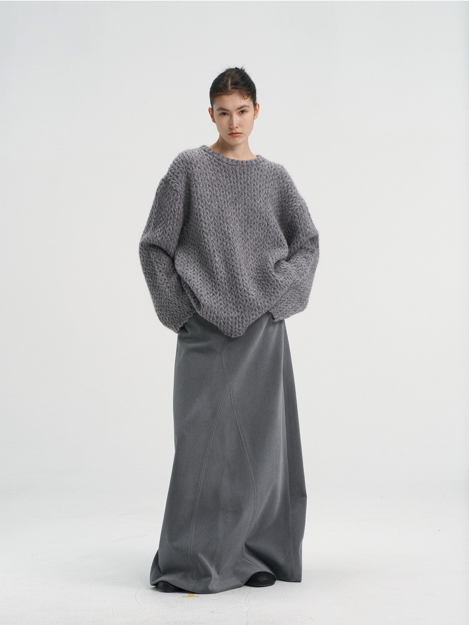 Front view of a women's oversized chunky wool blend knit sweater in heather grey, styled with a matching grey maxi skirt.