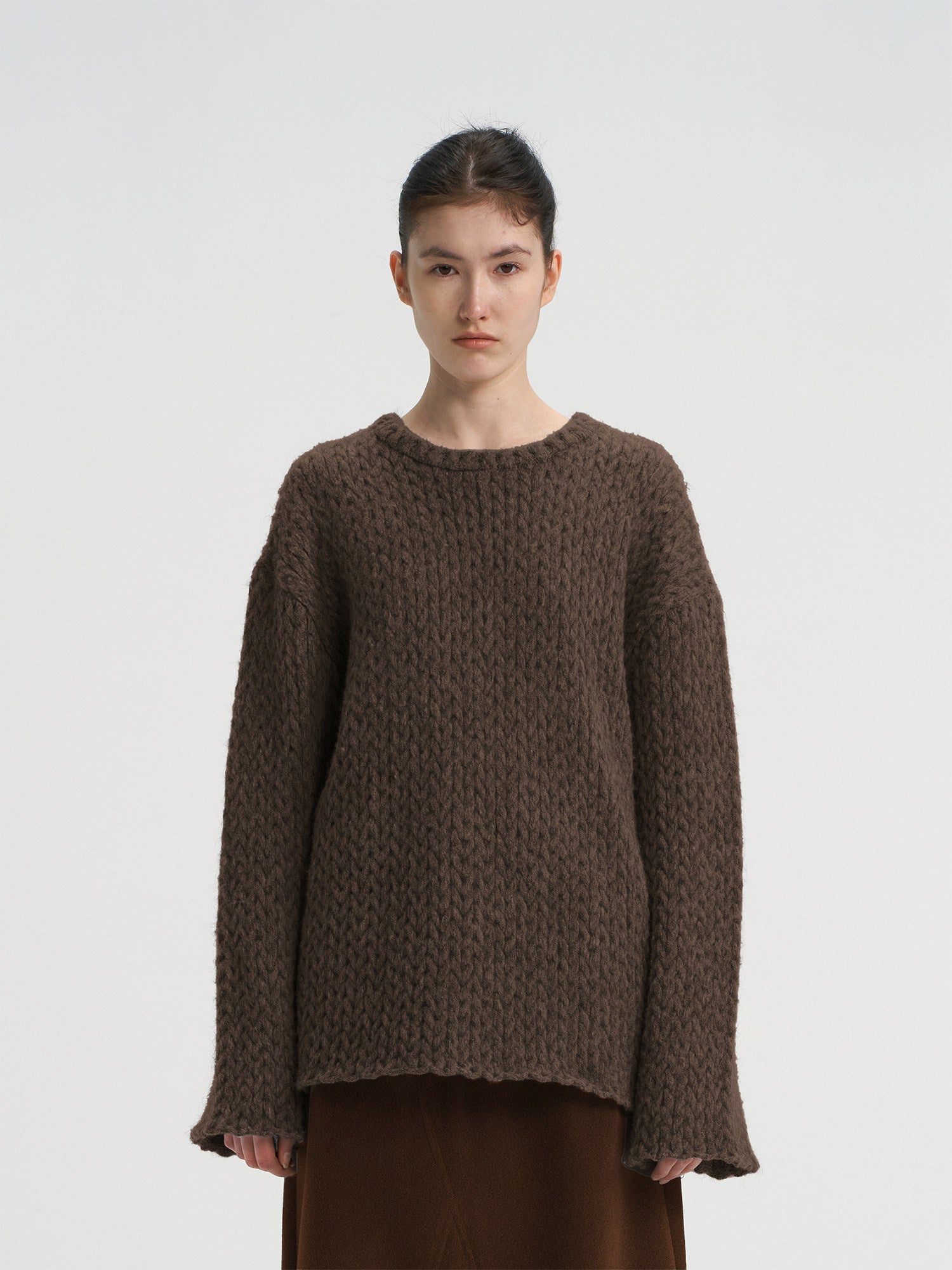 Close-up front view of a women's chocolate brown oversized wool blend sweater, featuring a chunky knit texture and round neck.