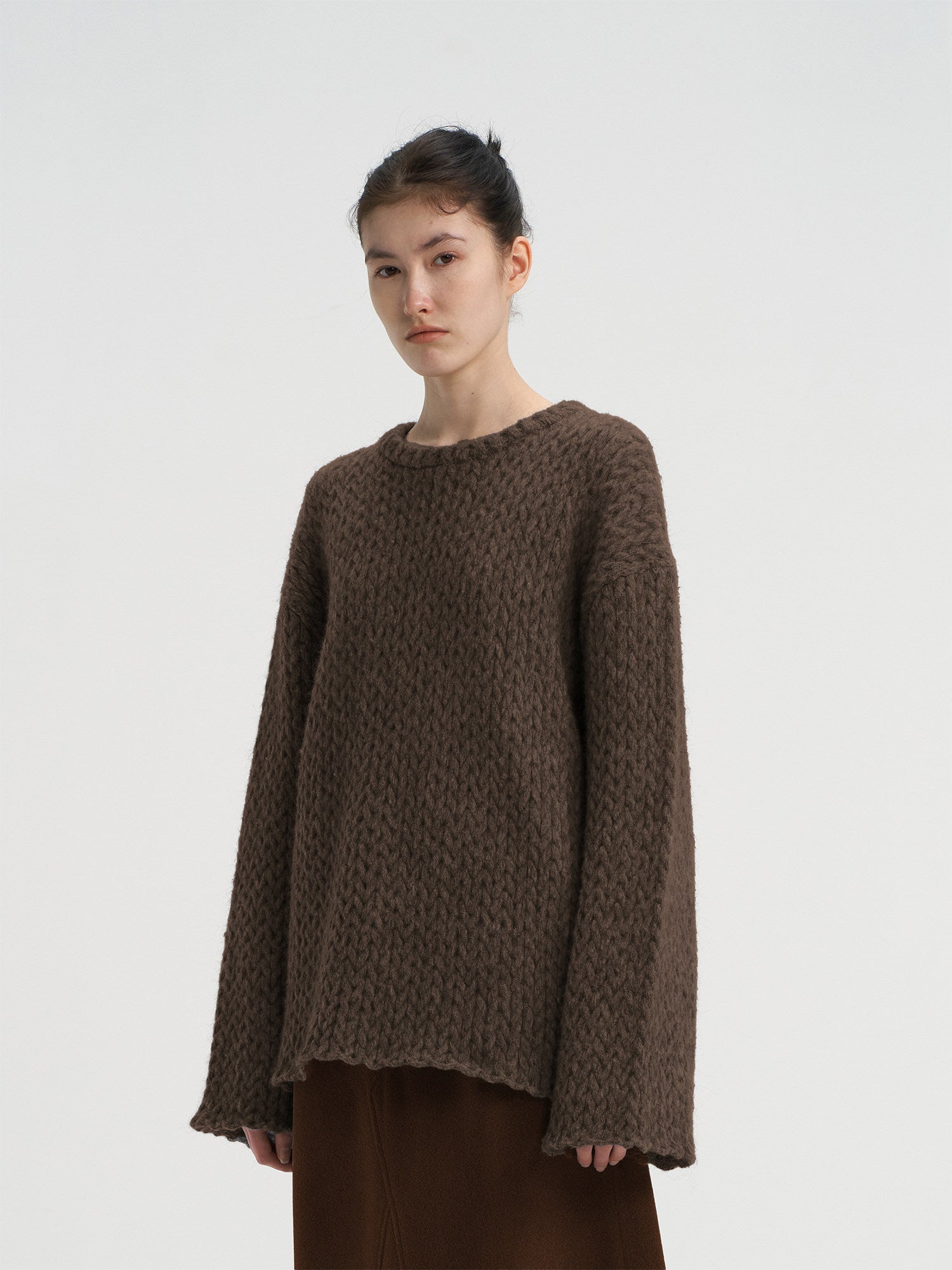 Close-up front view of a women's chocolate brown oversized wool blend sweater, featuring a chunky knit texture and round neck.