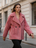 Model walking on a street wearing a dusty pink shearling wool double-breasted pea coat