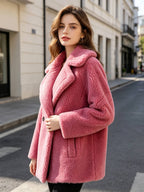 Three-quarter front portrait of a model wearing a dusty pink double-breasted shearling wool pea coat outdoors