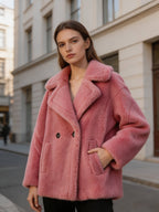 Model wearing a dusty pink shearling wool pea coat standing outdoors with one hand in her pocket