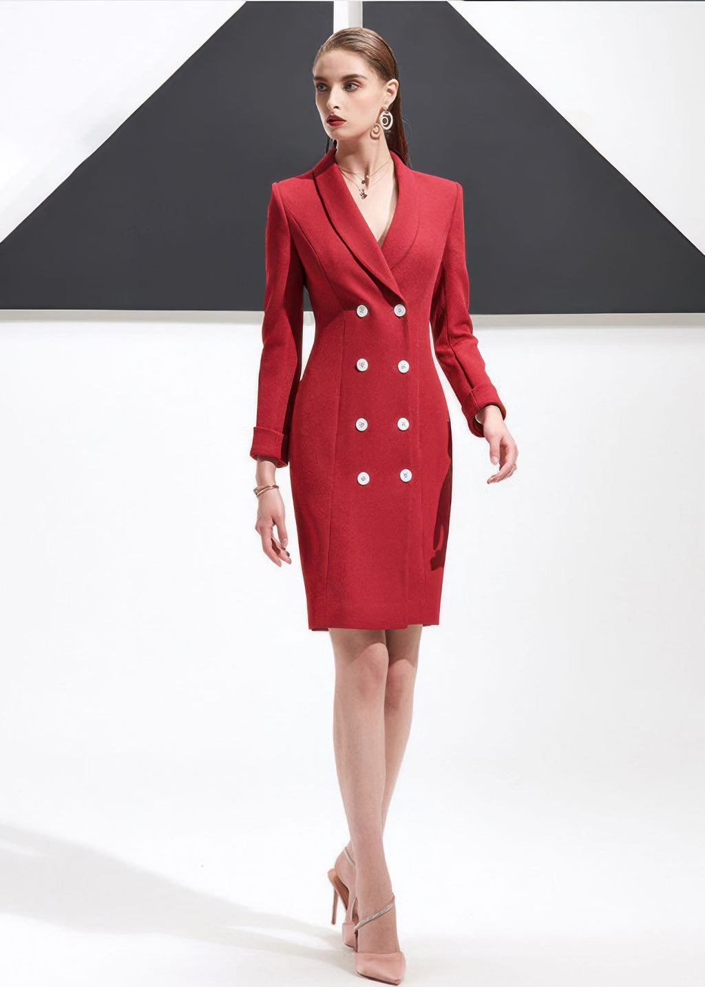 A woman walking with a slight side profile, wearing a structured red shawl lapel blazer dress with white double-breasted buttons and light pink heels.