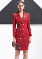 A close-up front view of a woman in a red blazer dress with white buttons, accessorized with a brooch and a burgundy clutch.