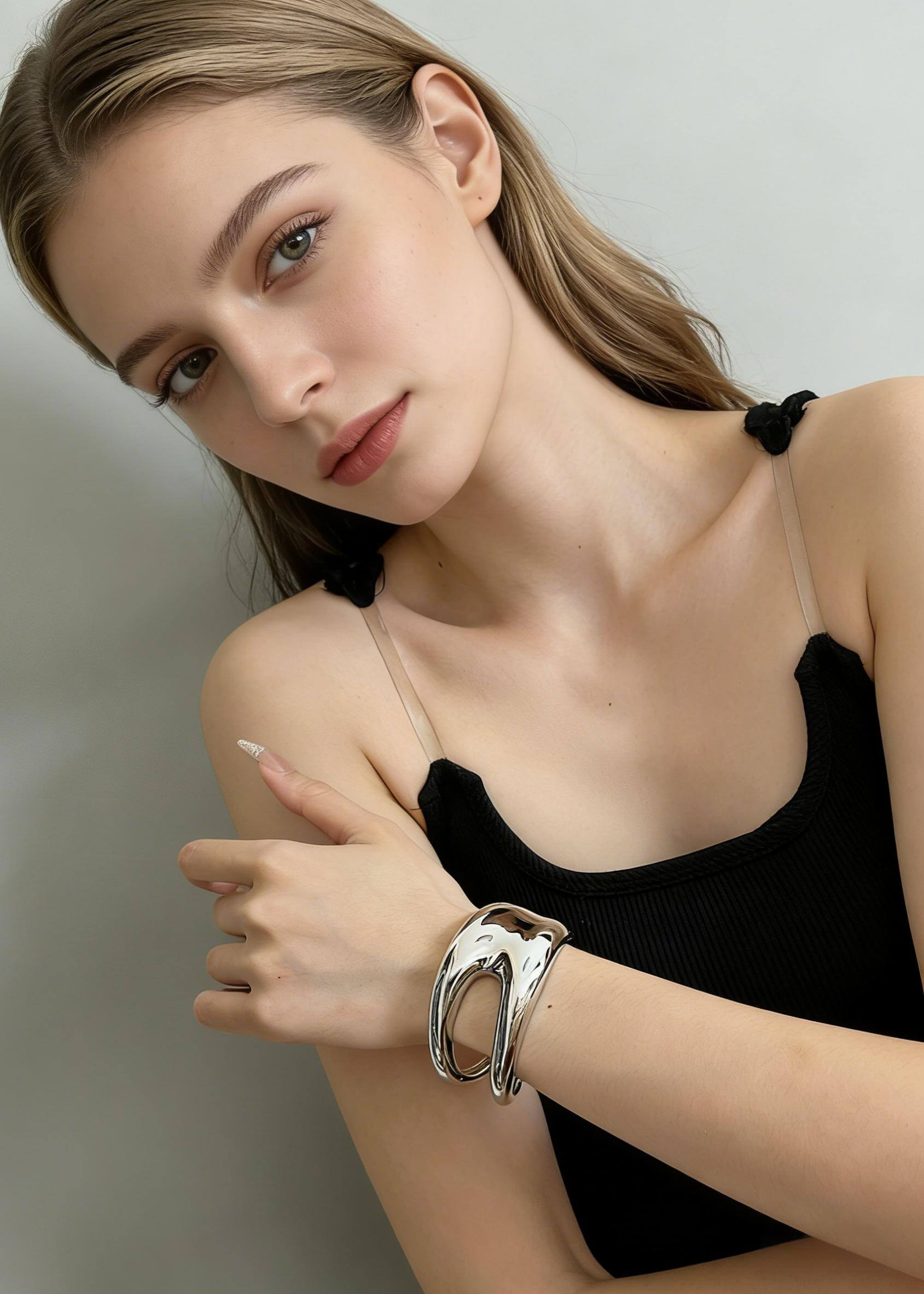 Close-up of a high-shine silver sculptural hollow cuff bracelet on a model’s wrist, showcasing the modern, fluid metal design.