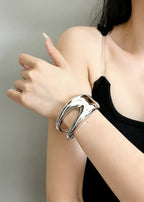 Minimalist silver sculptural hollow cuff metal bracelet worn with a black top, highlighting the bold, curved silhouette.