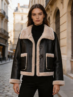 Front view of a women's black leather shearling-trimmed jacket paired with a black turtleneck