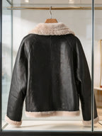 Back view of a women's black leather aviator jacket with plush beige shearling trim on hanger