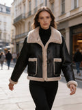 Woman walking down a city street wearing a cropped black leather aviator jacket with plush fleece lining