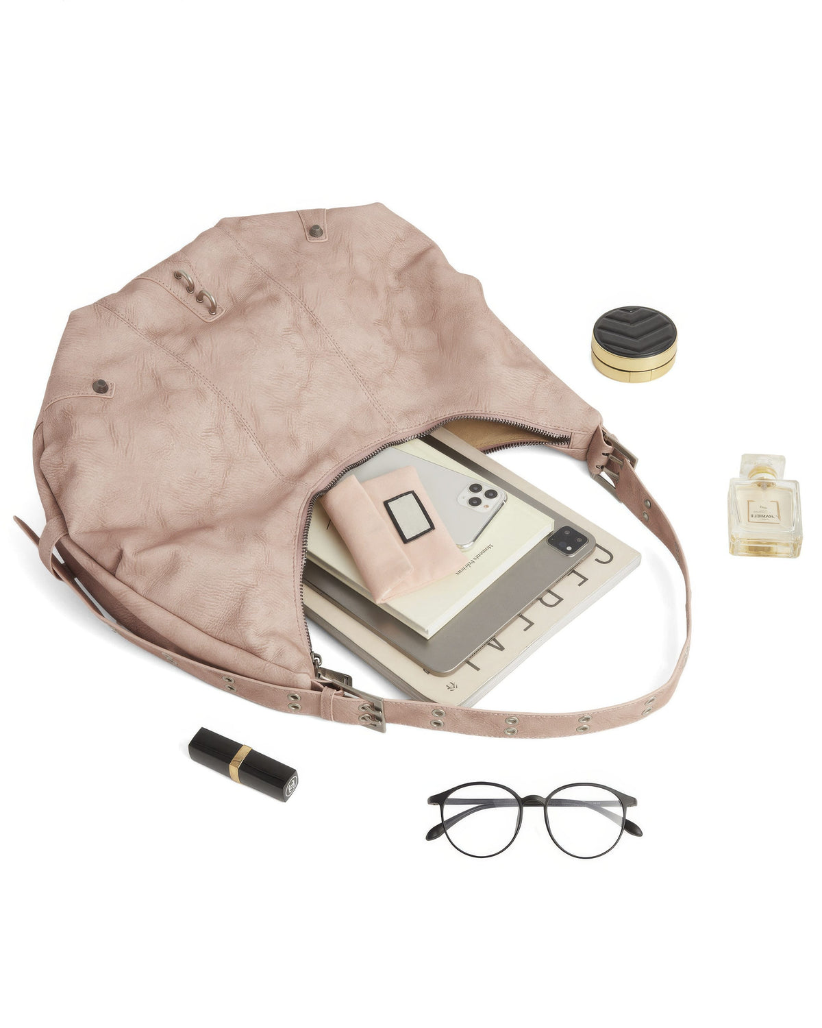 Flat lay of open dusty pink leather hobo tote filled with magazine, tablet, glasses, and beauty products