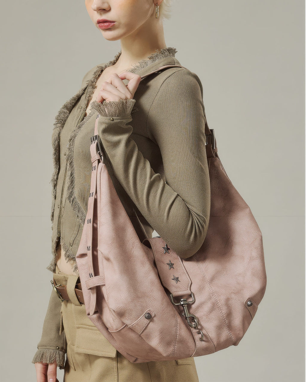 Close-up profile of model wearing a dusty pink star-studded soft faux leather crescent hobo bag